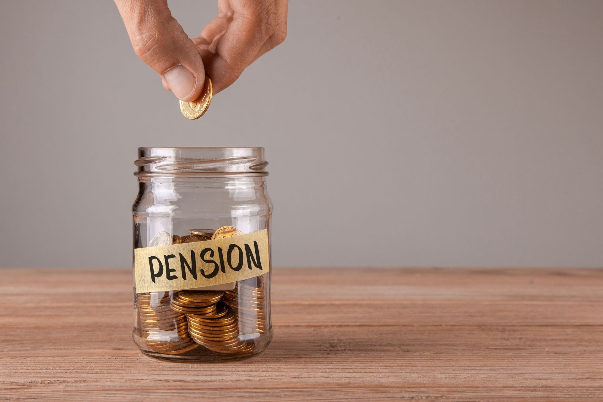 Pension. Glass jar with coins and an inscription pension. Man holds coin in his hand Pension. Glass jar with coins and an inscription pension. Man holds coin in his hand